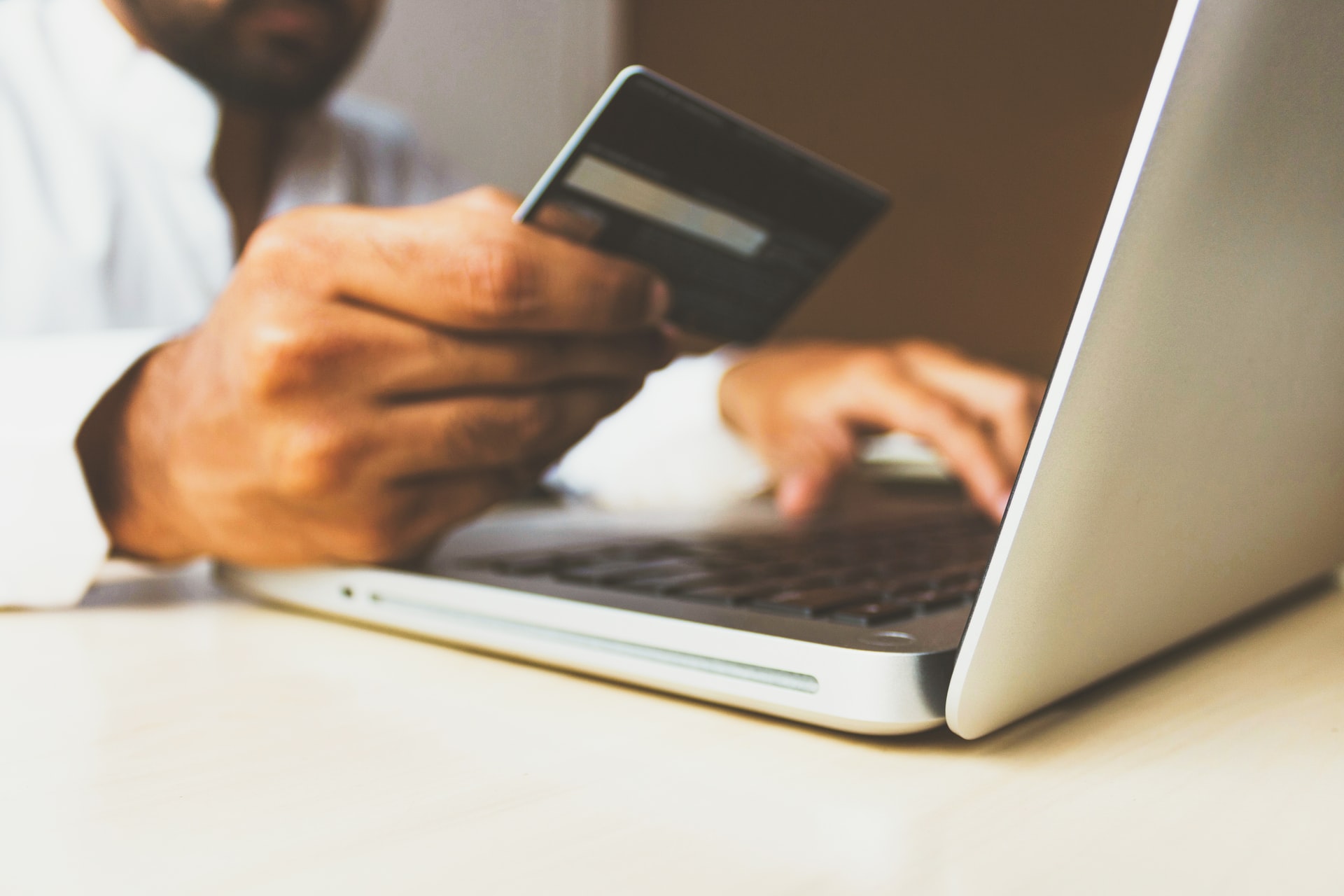 Person using a laptop with a credit card, indoors.